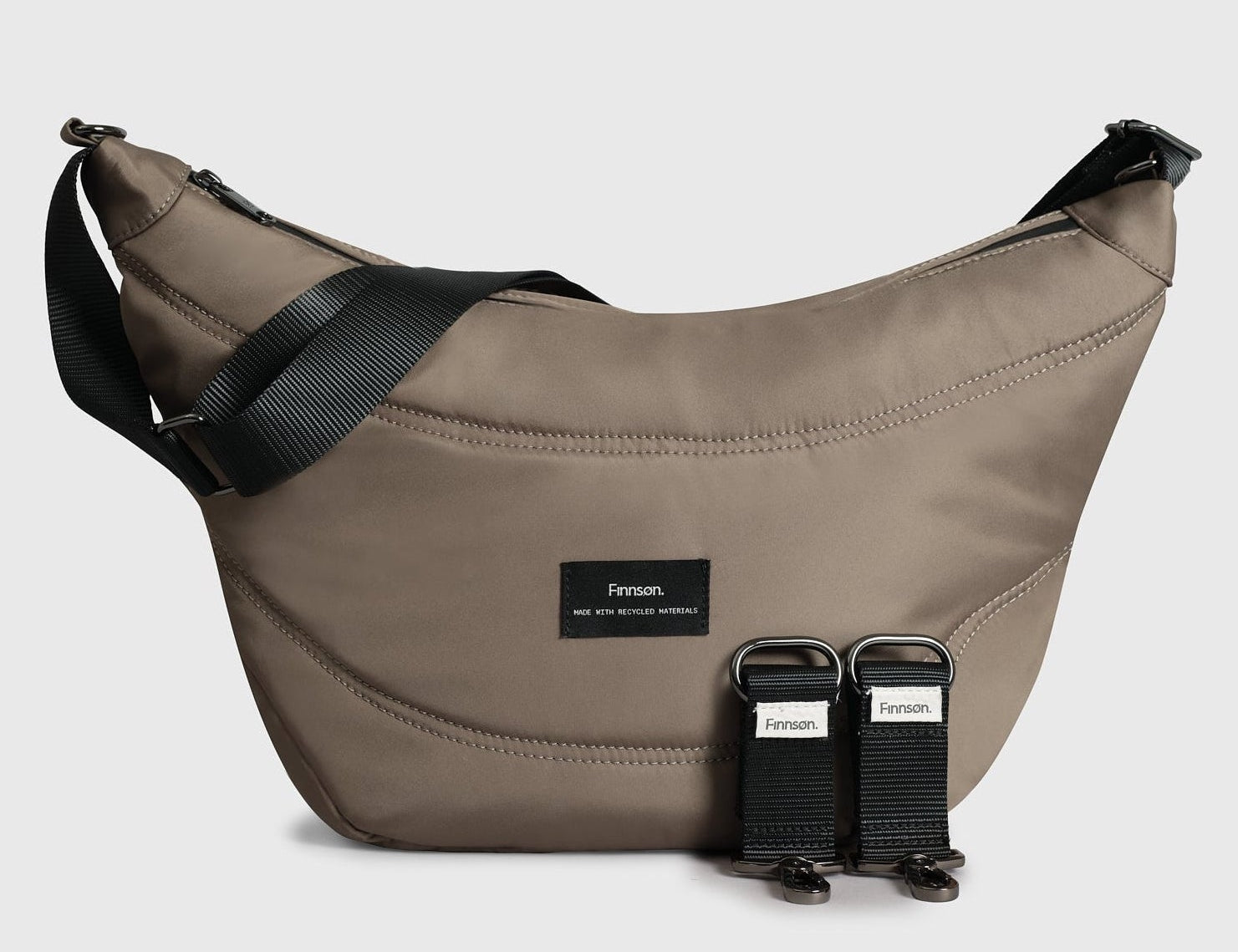 Osma Eco Stroller Organiser in Mocha: curved crossbody-style bag with black strap and two detachable stroller clips