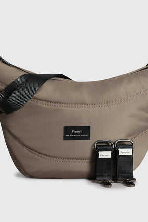 Osma Eco Stroller Organiser in Mocha: curved crossbody-style bag with black strap and two detachable stroller clips