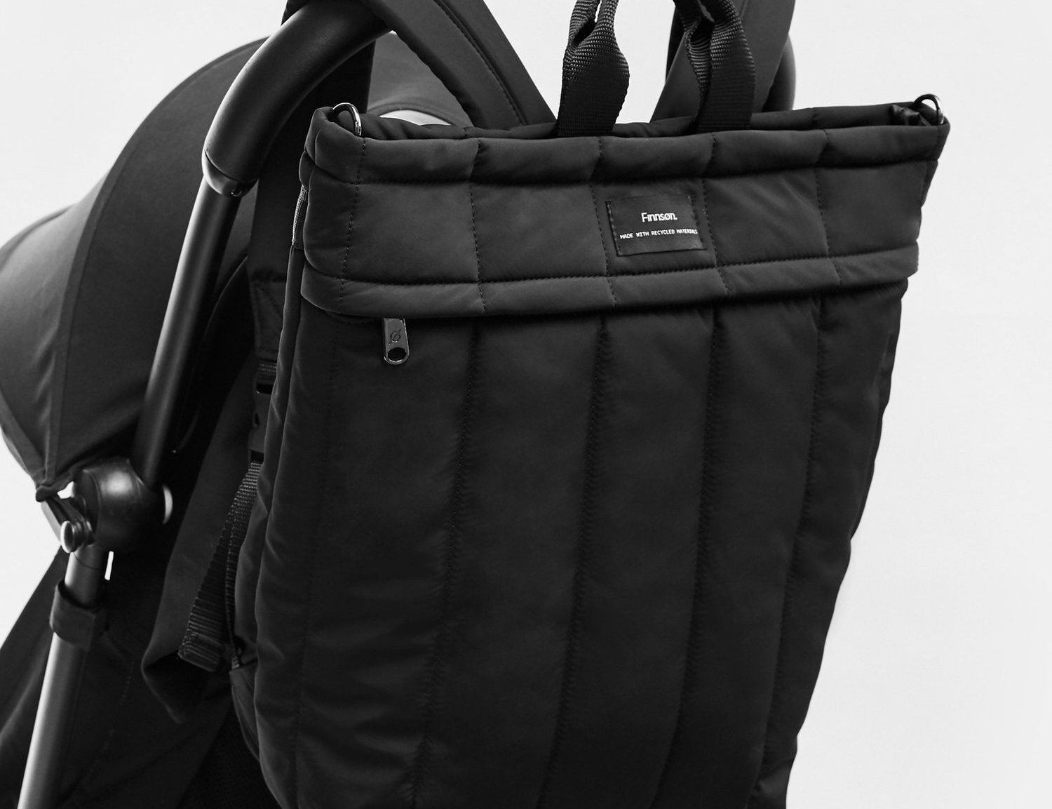 Black stroller bag attached to a stroller on a light gray background