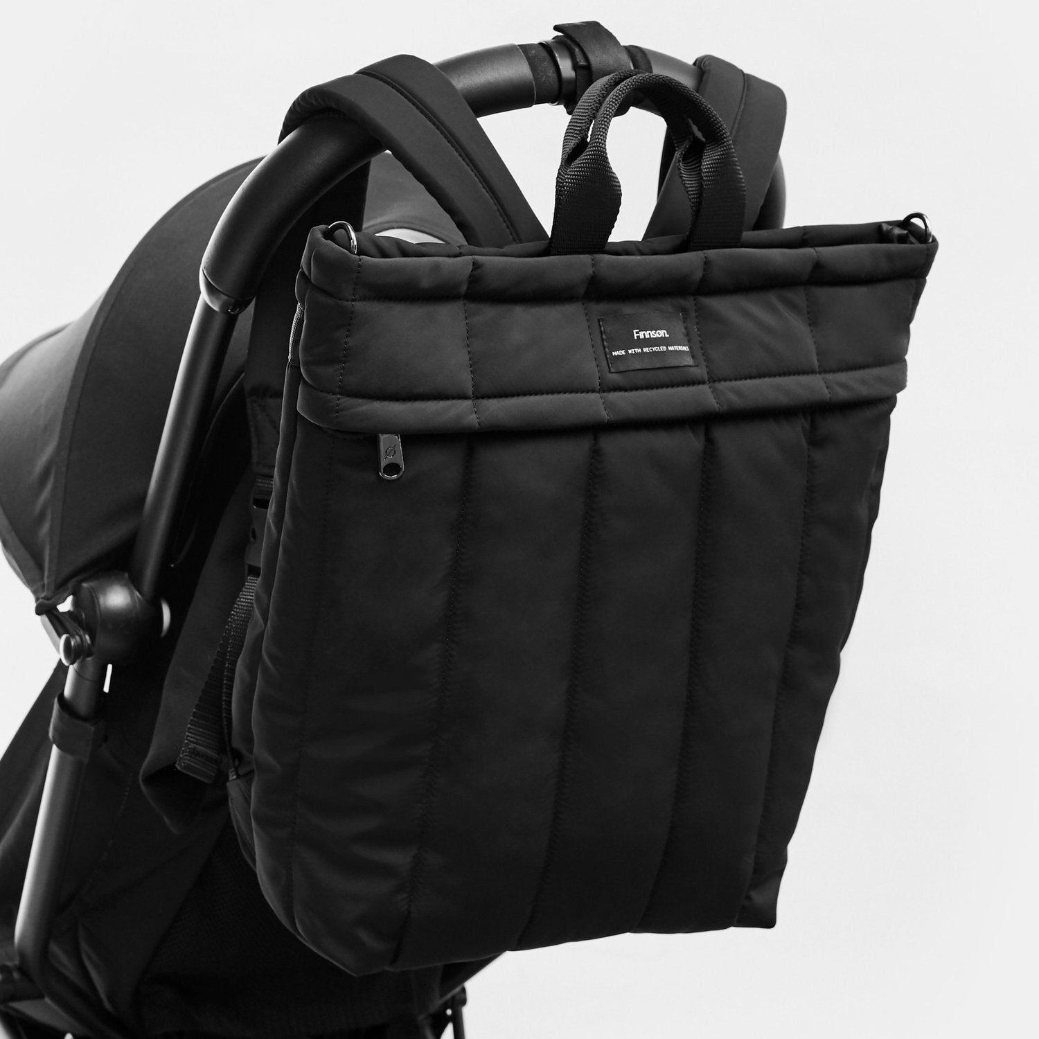 Black stroller bag attached to a stroller on a light gray background