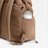 Elise Eco Changing Backpack Mocha, side view with a baby bottle in the side pocket and a shoulder strap in view