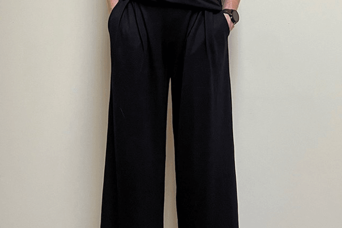 Person wearing a black outfit with wide-leg pants against a plain background