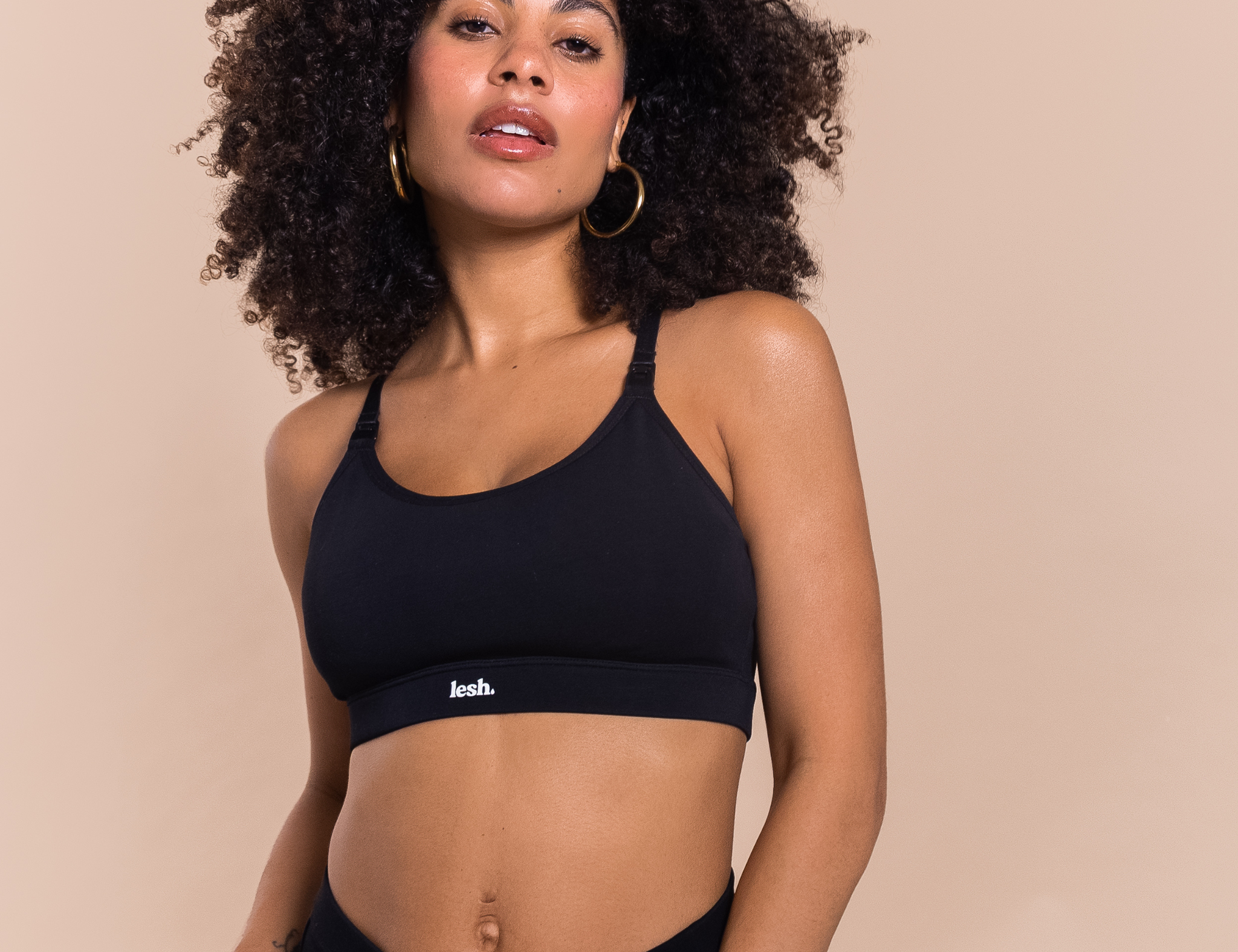 Woman wearing a black sports bra and leggings with 'Leash' branding on a beige background