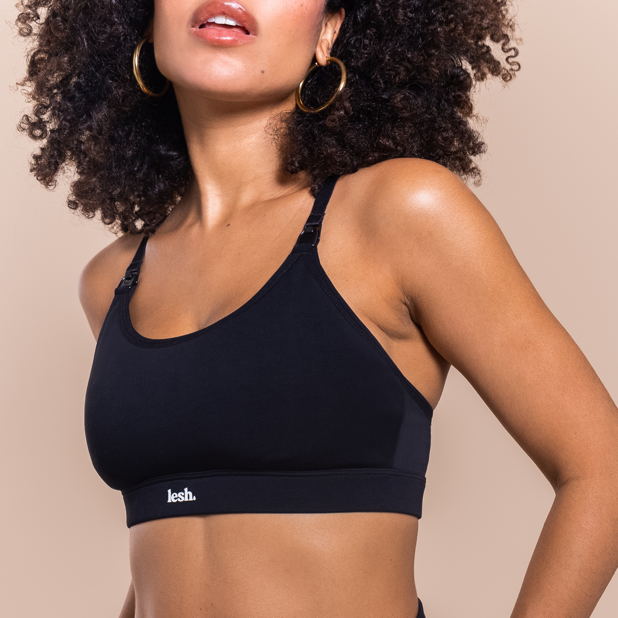 Woman wearing a black sports bra with 'lesh' branding on a beige background