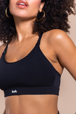 Woman wearing a black sports bra with 'lesh' branding on a beige background