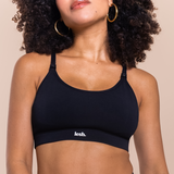 Woman wearing a black sports bra with 'lesh' branding on a beige background
