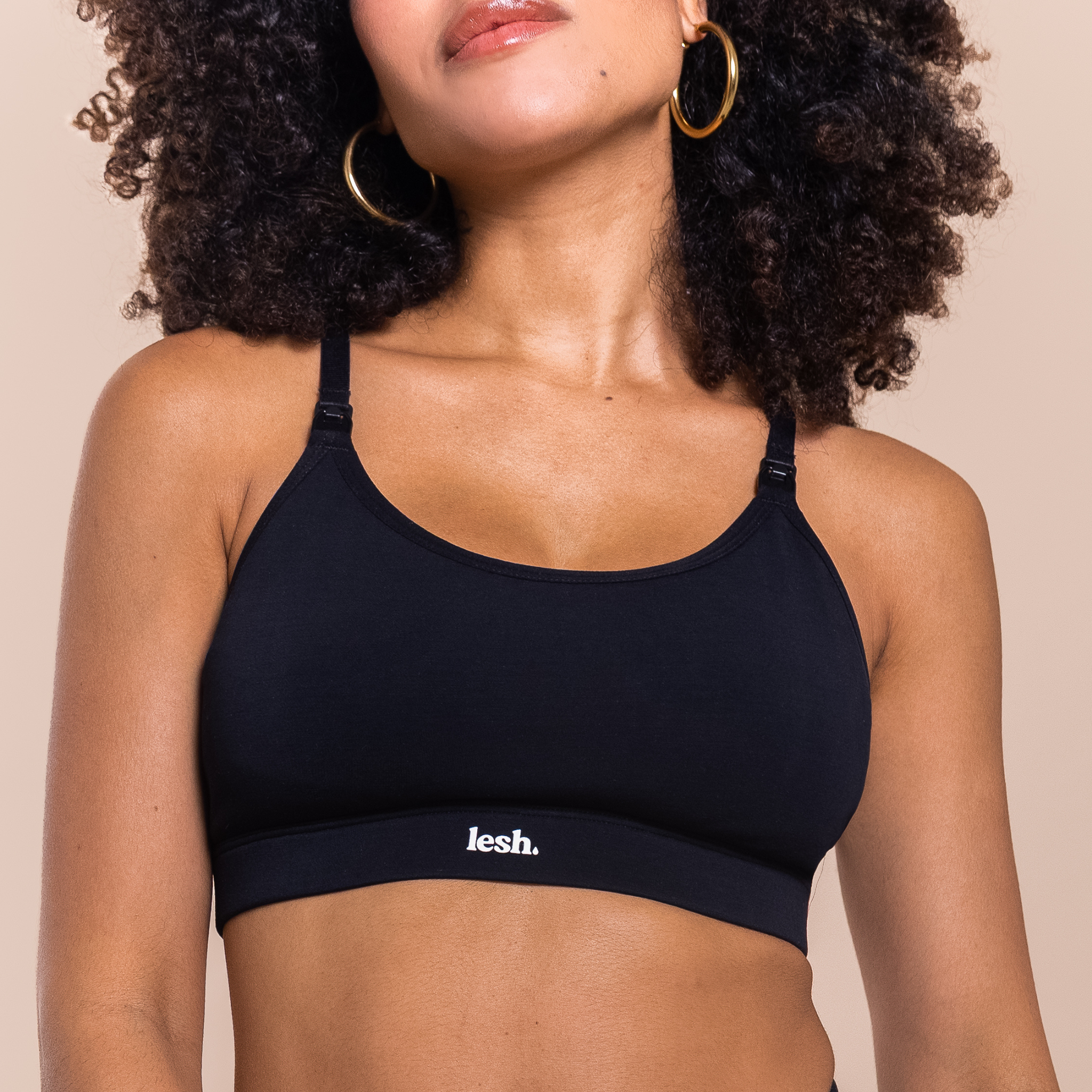 Woman wearing a black sports bra with 'lesh' branding on a beige background