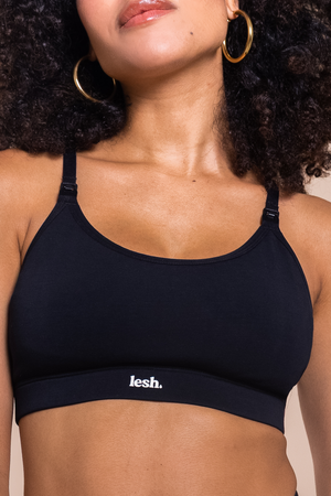 Woman wearing a black sports bra with 'lesh' branding on a beige background