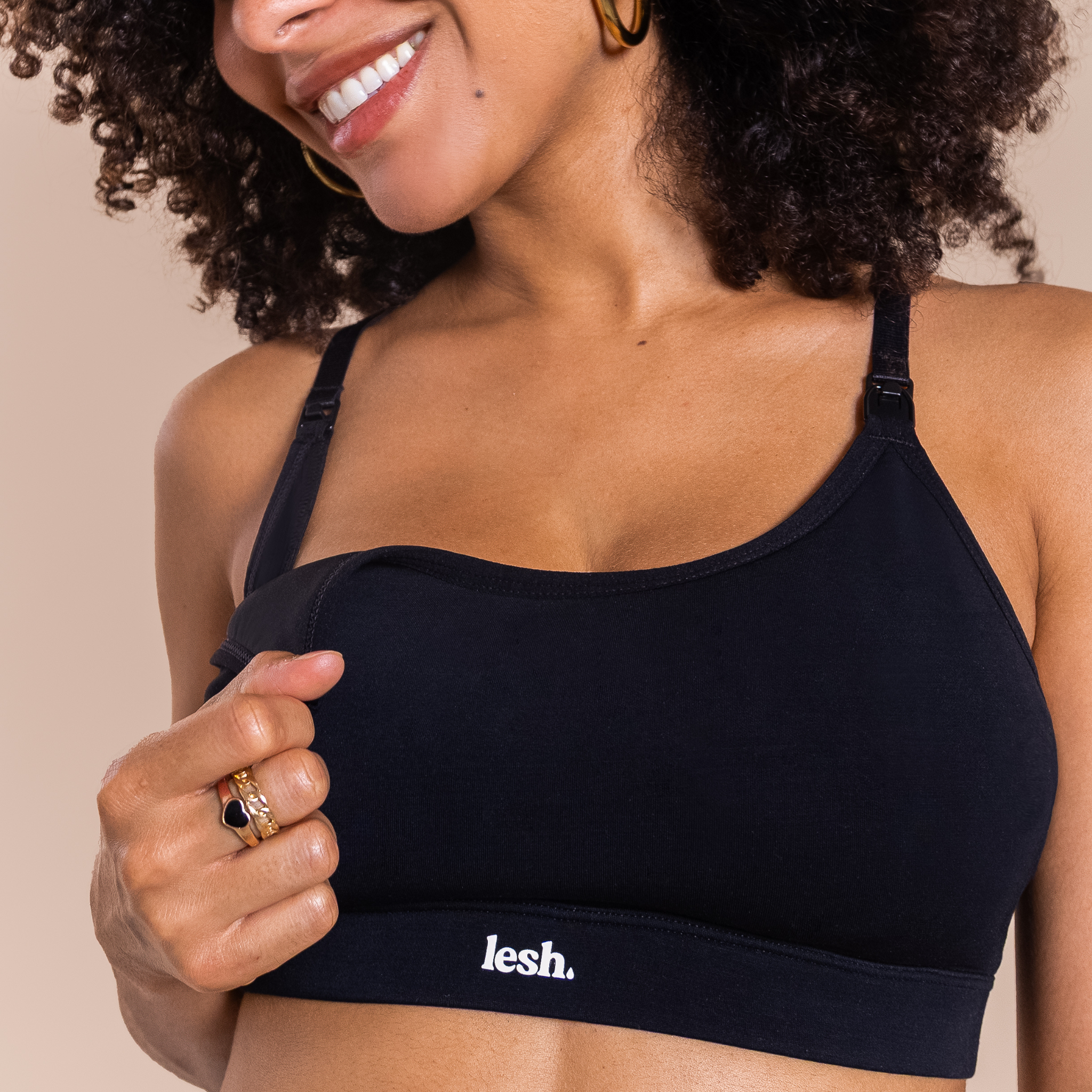 Woman wearing a black sports bra with 'lesh' branding on a beige background