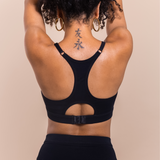 Person wearing a black sports bra with cut-out design on a beige background