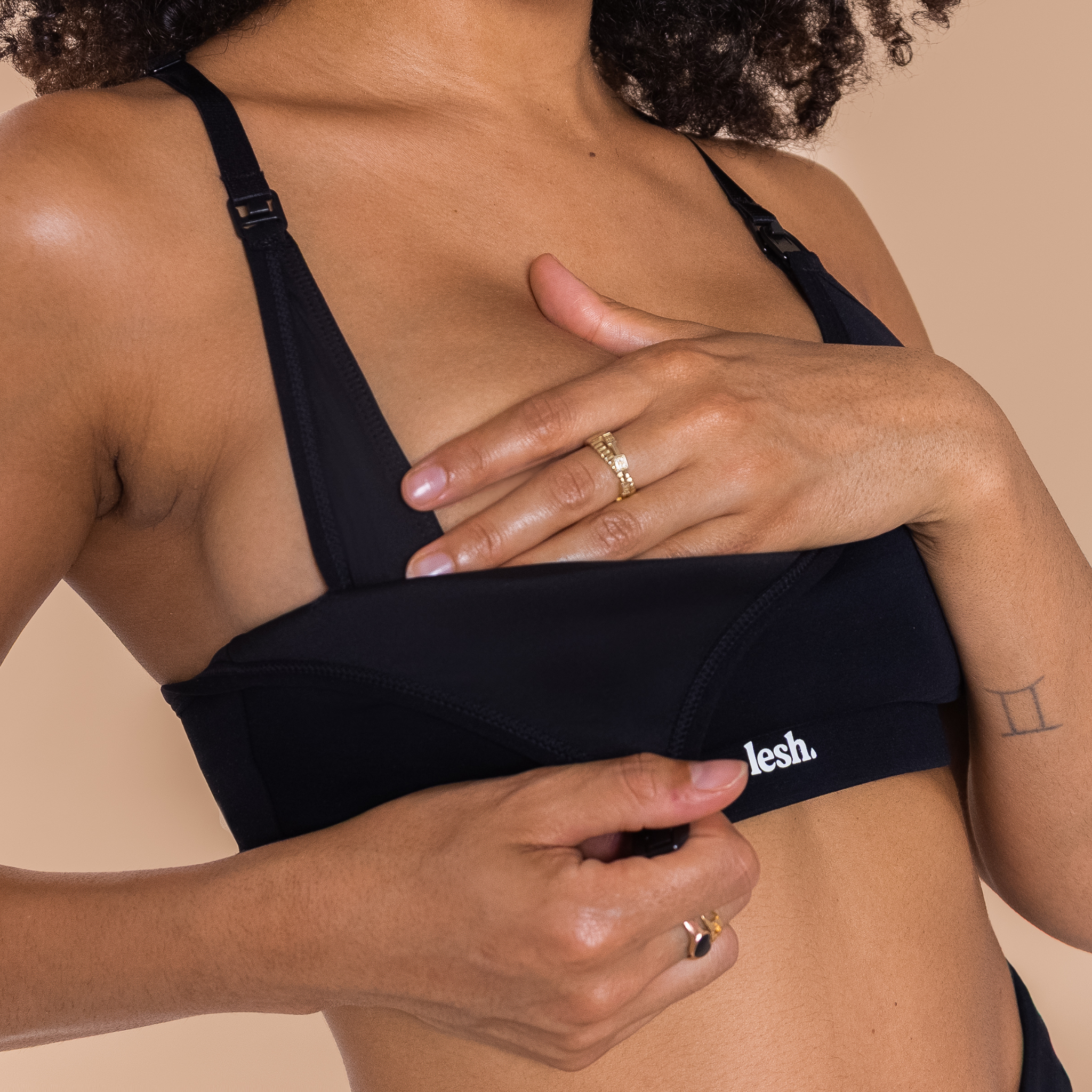 Person wearing a black bikini top with 'leslie' branding on a beige background