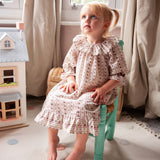 Beatrice Rose Stripe nightie, child sitting on a small green chair showing the ruffled collar, sleeves and hem