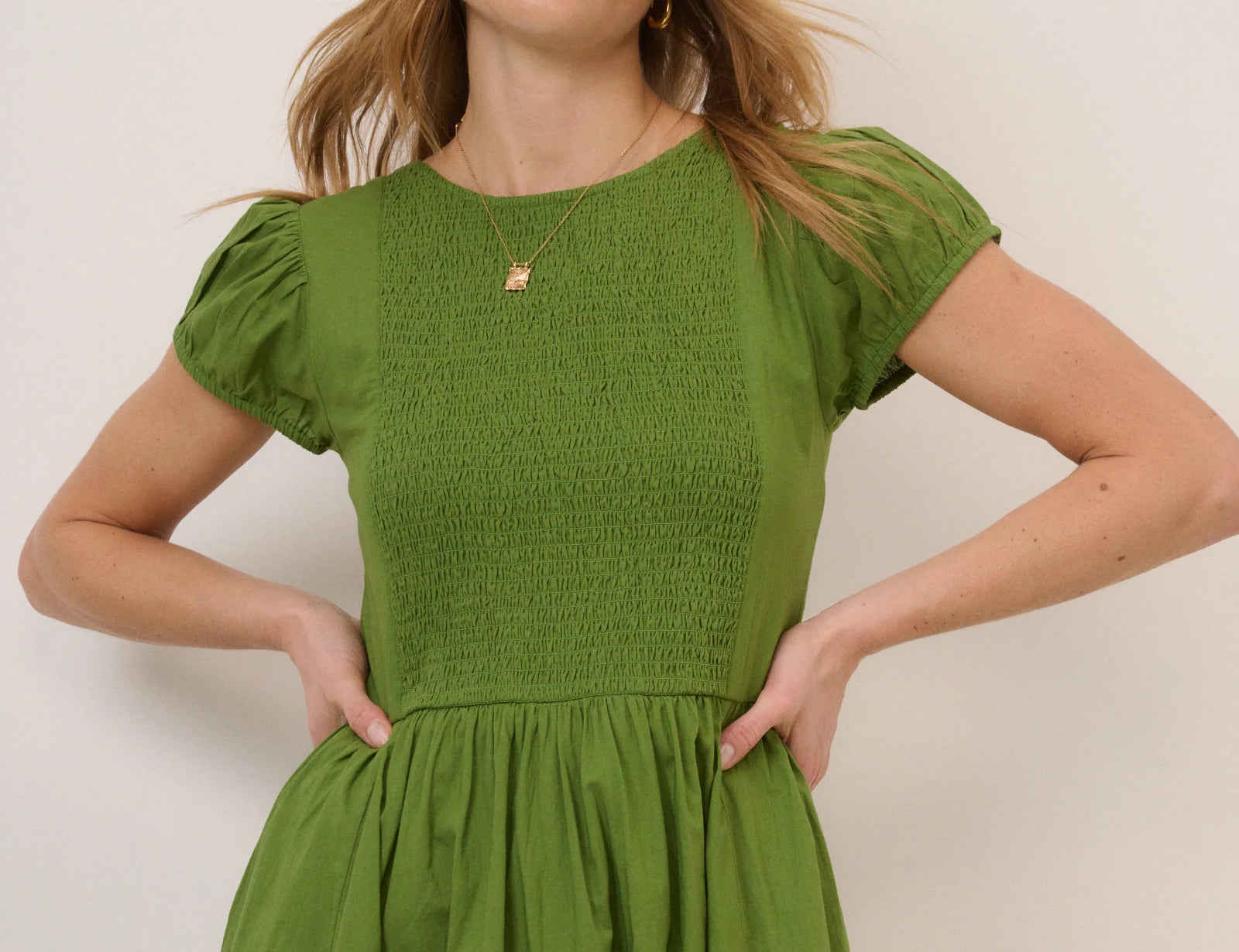 Woman wearing a green dress against a plain background