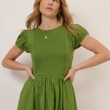 Woman wearing a green dress against a plain background