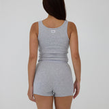 A woman shown from the back wearing a heather gray sleeveless tank top and matching high-waisted shorts against a plain light gray studio background.
