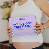 A woman in a white ribbed tank top holds a lavender gift box with blue text that reads 'bloom blossom' and 'YOU'VE GOT THIS MAMA'.