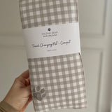 Checkered travel changing mat with Ralphie Bear branding held by a hand against a neutral background