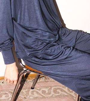 Person wearing a blue outfit sitting on a chair with a patterned rug below.