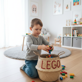 LEGO belly basket, large, on a playroom floor with a child kneeling and putting toy bricks into it