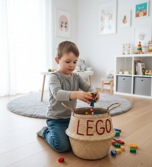 LEGO belly basket, large, on a playroom floor with a child kneeling and putting toy bricks into it