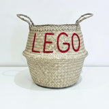 LEGO belly basket, large, front view of woven basket with red LEGO lettering and two looped handles on a white surface