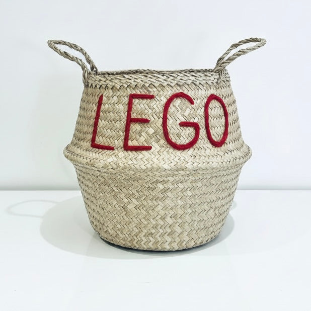 LEGO belly basket, large, front view of woven basket with red LEGO lettering and two looped handles on a white surface