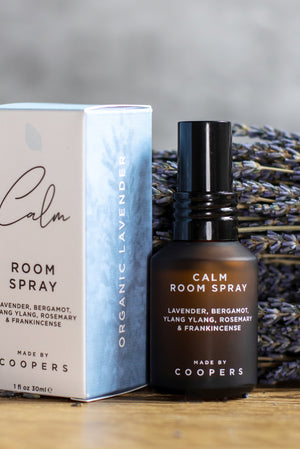 Calm Room Spray bottle standing beside its box in front of dried lavender on a wooden surface