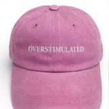 Pink cap with 'OVERSTIMULATED' text on a white background