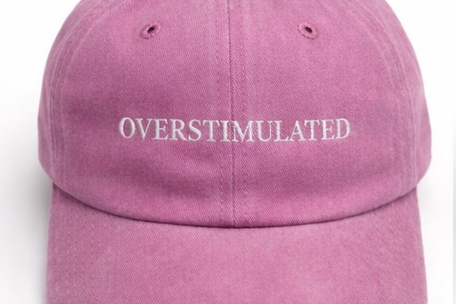 Pink cap with 'OVERSTIMULATED' text on a white background