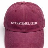 Maroon cap with 'OVERSTIMULATED' text on a white background