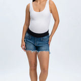 Woman wearing a white tank top and blue denim shorts on a white background