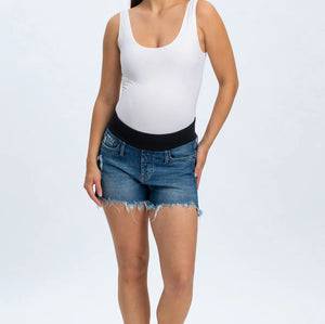 Woman wearing a white tank top and blue denim shorts on a white background