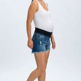 Woman wearing a white tank top and blue denim shorts on a white background