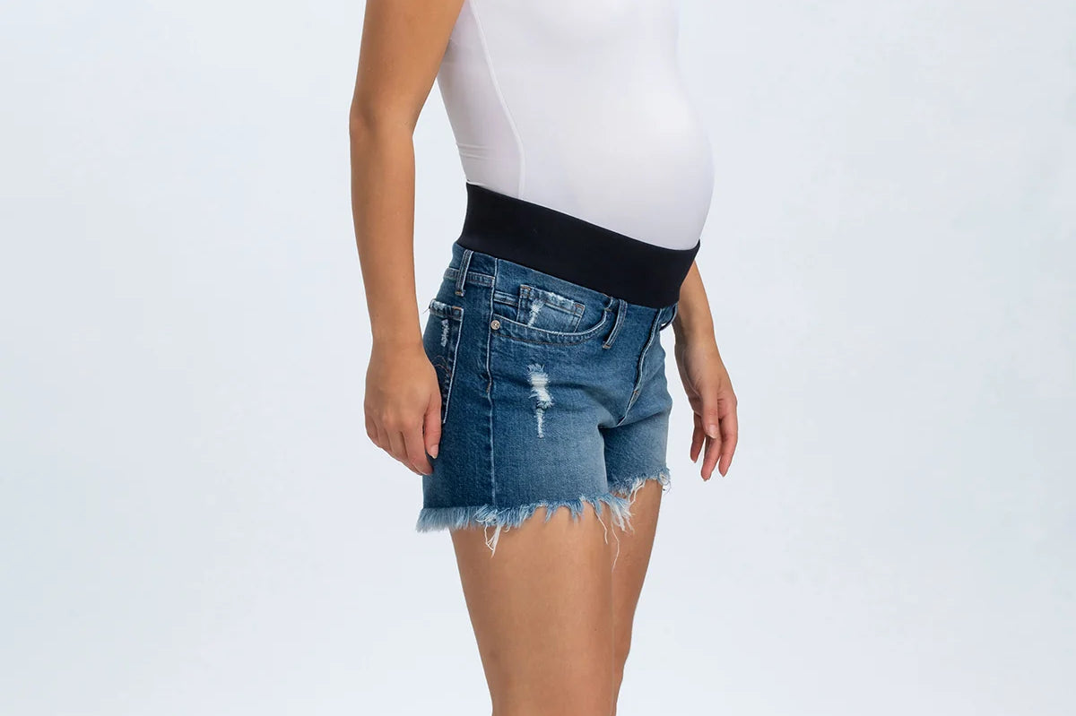 Woman wearing a white tank top and blue denim shorts on a white background