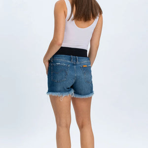 Woman wearing a white tank top and blue denim shorts on a white background