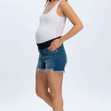 Woman wearing a white tank top and denim shorts on a white background