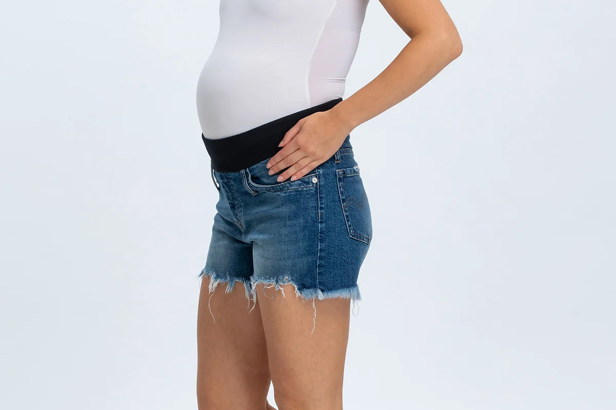 Woman wearing a white tank top and denim shorts on a white background
