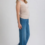 Woman wearing a beige top and blue jeans on a white background