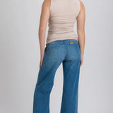 Woman wearing blue jeans and a beige top on a white background