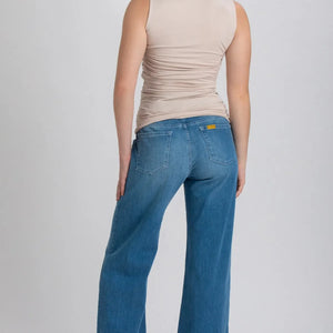 Woman wearing blue jeans and a beige top on a white background