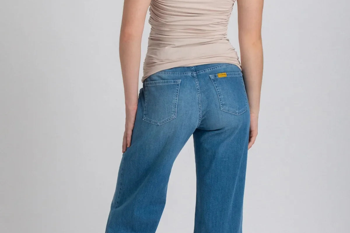Woman wearing blue jeans and a beige top on a white background