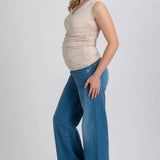 Woman wearing a beige sleeveless top and blue jeans on a white background