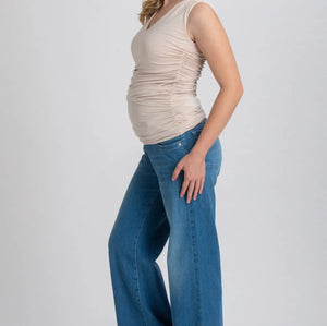 Woman wearing a beige sleeveless top and blue jeans on a white background