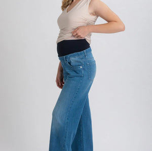 Woman wearing a beige top and blue jeans on a white background