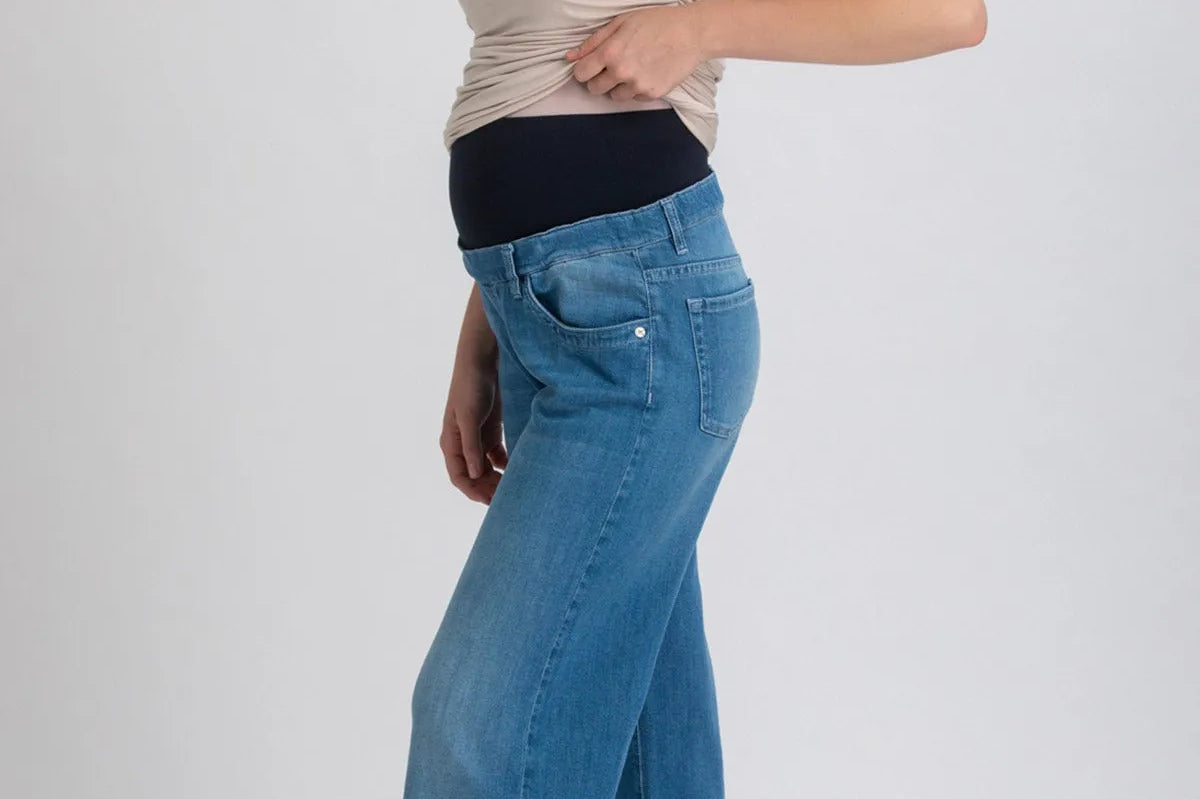 Woman wearing a beige top and blue jeans on a white background