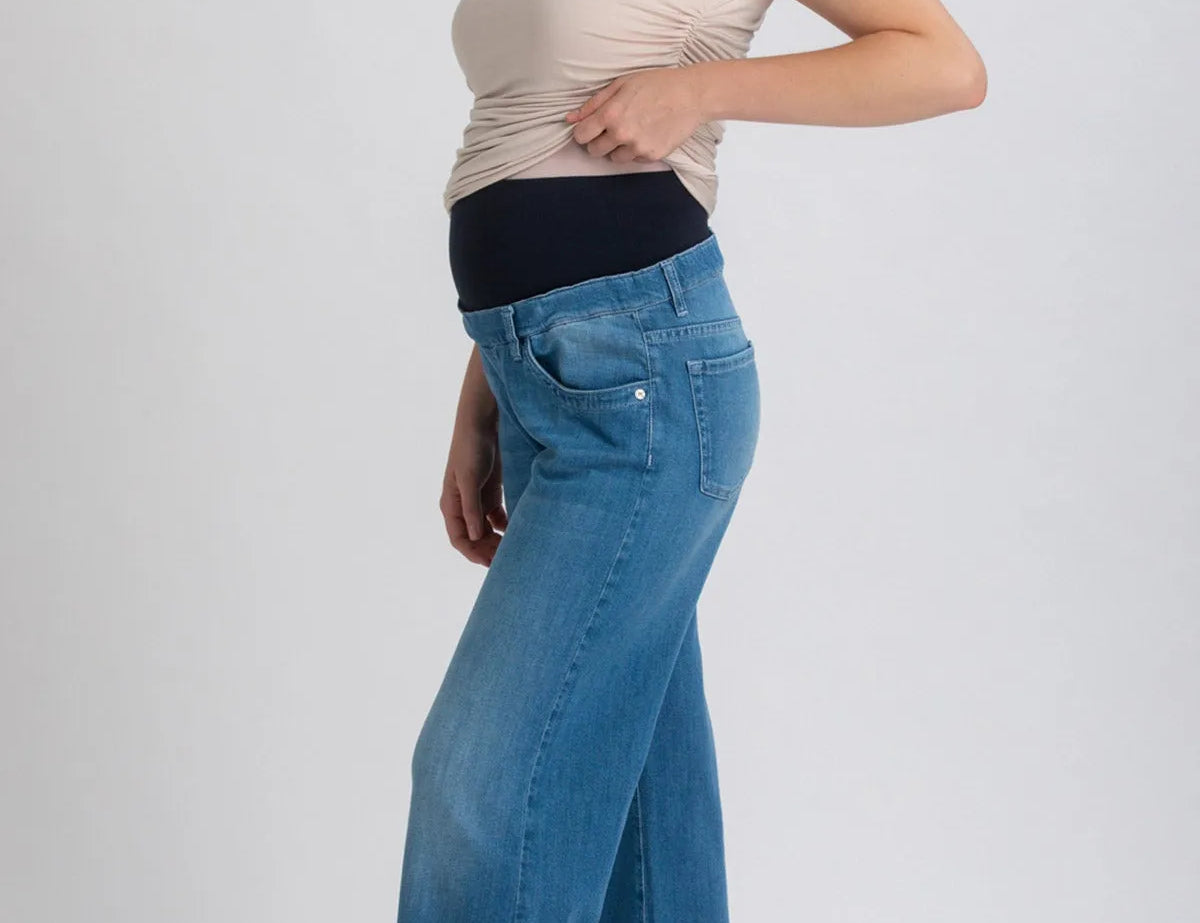 Woman wearing a beige top and blue jeans on a white background
