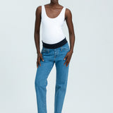 Woman wearing blue maternity jeans and white vest top