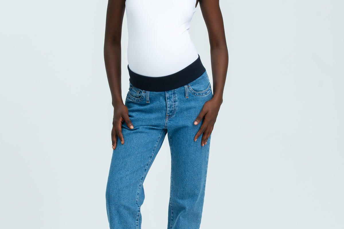 Woman wearing blue maternity jeans and white vest top