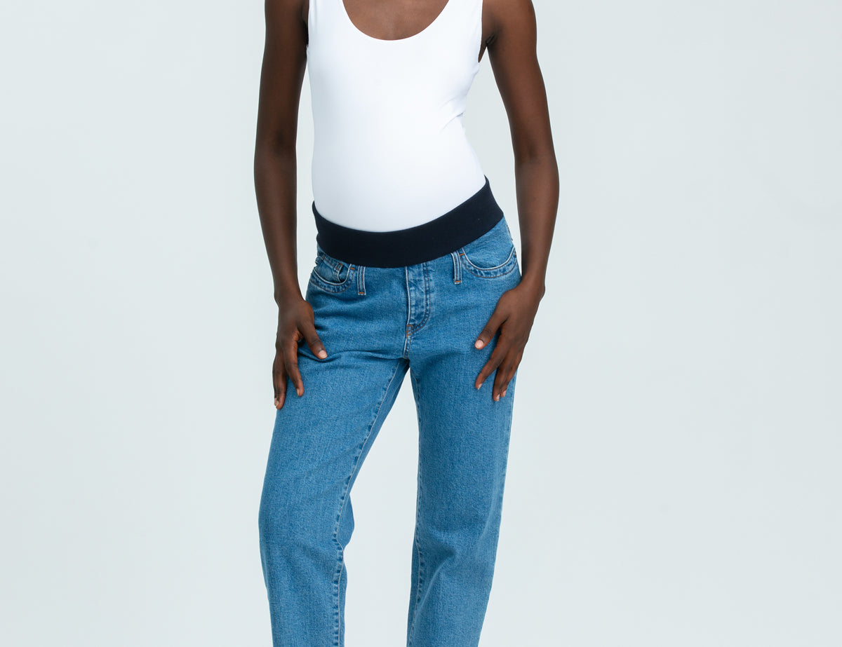 Woman wearing blue maternity jeans and white vest top