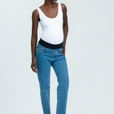 Woman wearing blue maternity jeans and white vest top